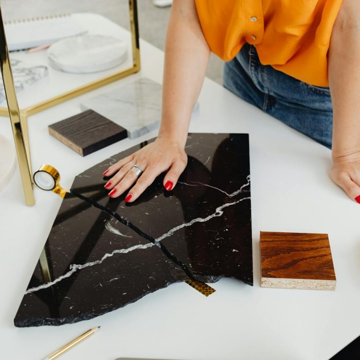 A Person in Orange Shirt Holding Black Marble Tile on White Table